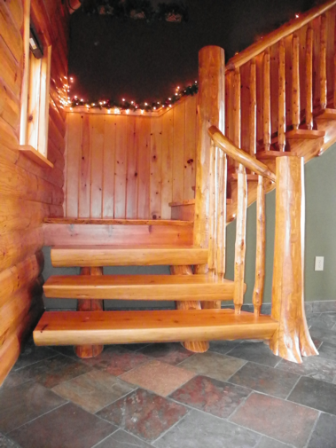 Custom rustic log stairs and log railings in a log home by Adirondack LogWorks