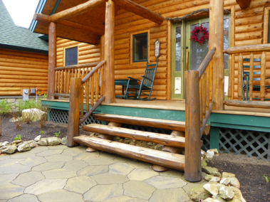 Custom rustic log stairs on the front of a log home by Adirondack LogWorks