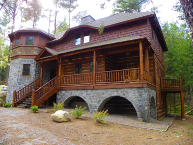Custom rustic log truss and entryway, log railings, log stairs, and siding by Adirondack LogWorks