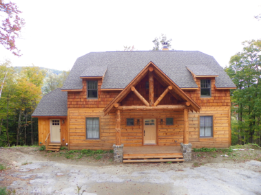 Custom rustic log truss and entryway on a log home by Adirondack LogWorks