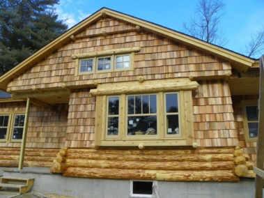 Custom rustic log siding and log trim woodwork on a log home by Adirondack LogWorks