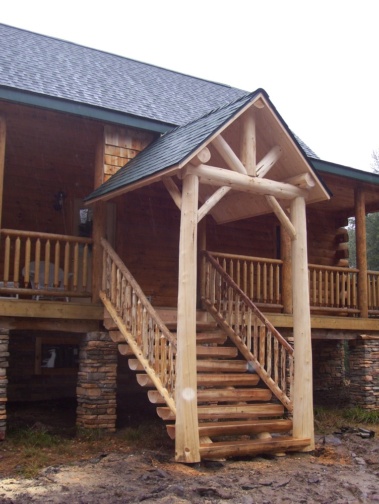 Custom log entryway with rustic truss, railing, and stair woodwork by Adirondack LogWorks