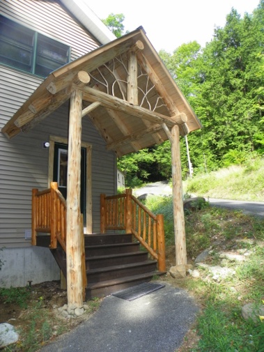 Custom rustic log entryway, truss, post, twig, and railing woodwork by Adirondack LogWorks