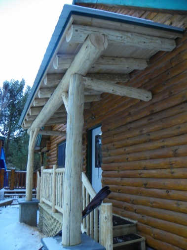 Custom rustic log truss, entryway, and railing woodwork at a log home by Adirondack LogWorks