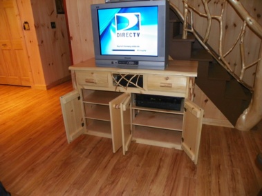 Custom-made rustic log entertainment unit with doors, drawers, twig woodwork, and log trim by Adirondack LogWorks