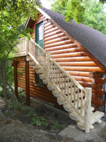 Custom rustic log stairs and railings on a log home by Adirondack LogWorks