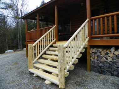 Custom rustic log stairs and railings on a log home by Adirondack LogWorks