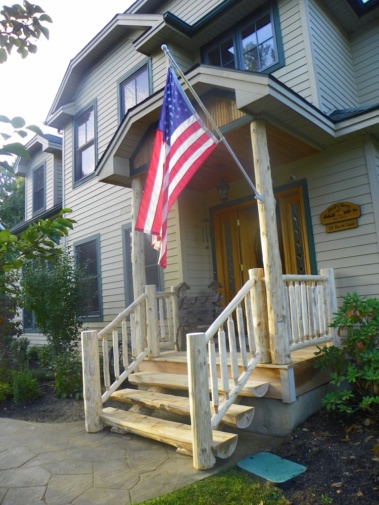 Custom rustic log entryway with log railings and half-log stairs by Adirondack LogWorks